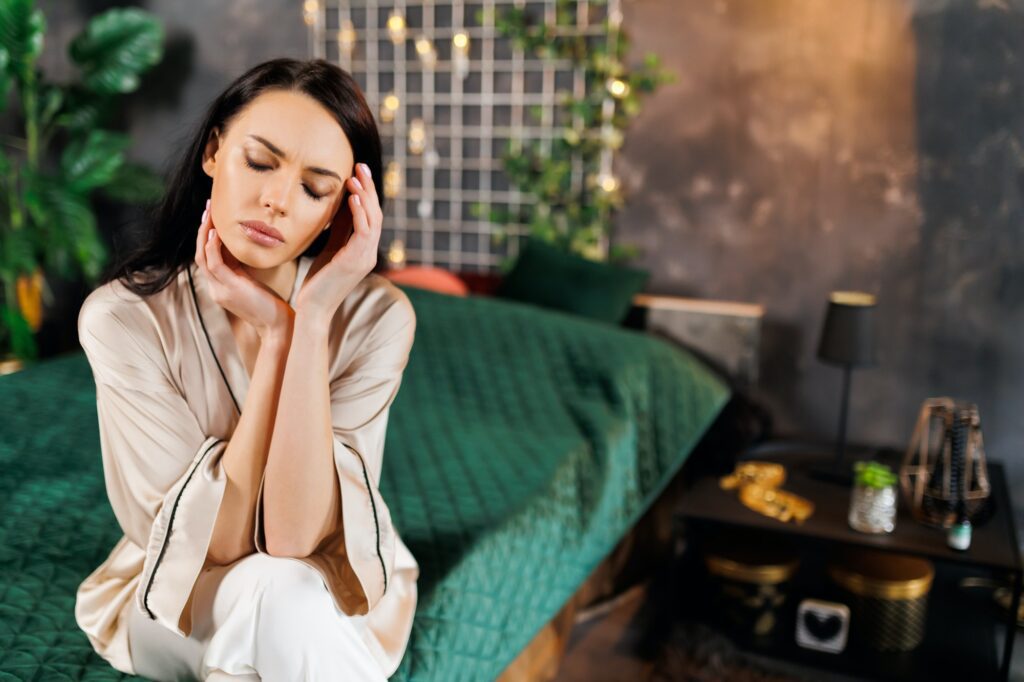 sad Woman sitting on bed and having headache.